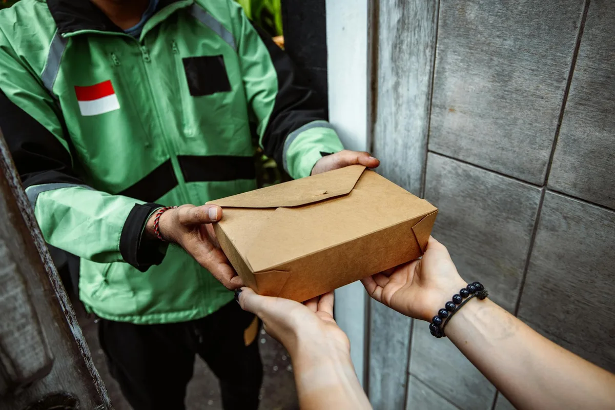 Kurir mengantarkan paket ke tangan pembeli sebagai ilustrasi layanan COD