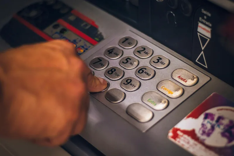 Tangan menekan tombol ATM – representasi proses penarikan saldo ke rekening bank